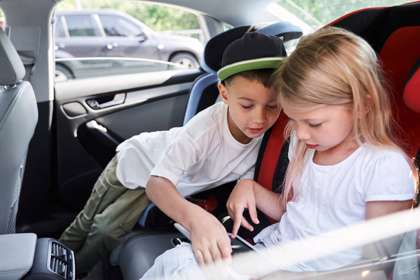 Happy kids playing on tablet in car - 写真・画像