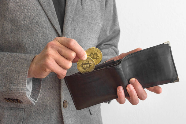 Uomo d'affari indossa un abito, in possesso di un portafoglio e Bitcoin BTC crypto valuta monete d'oro, nuovo concetto di denaro virtuale. Tecnologia mineraria o blockchain - Foto, immagini