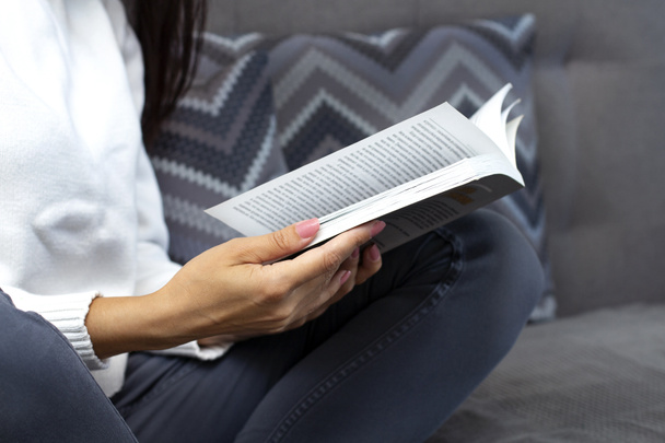 Jeune femme lisant le livre, gros plan, sur le fond intérieur de la maison. Une étudiante est formée. Rester concept maison. - Photo, image