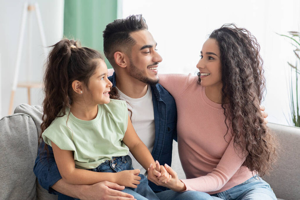 Prima la famiglia. felice arabo mamma, papà e figlia abbracciare su divano - Foto, immagini