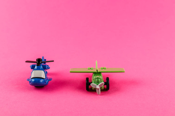 Small plastic airplane and helicopter with copy space on pink background. Toys. - Photo, image