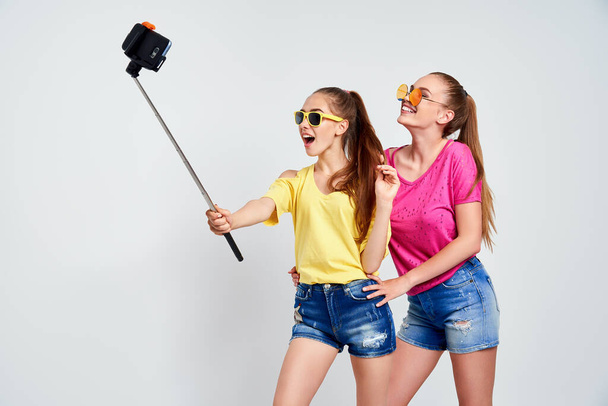 portrait of happy teenagers taking selfie together isolated on whitePortrait of happy teenagers in summer clothes, sunglasses taking selfie together isolated on white. - Foto, afbeelding