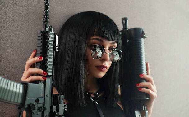 丸メガネの自動小銃を持った女性殺人者の肖像画です - 写真・画像