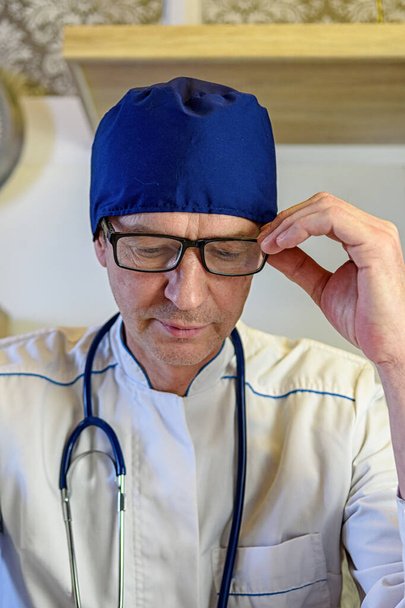 Valkotakkinen lääkäri kuuntelee potilaan ongelmia kotona. Terveydenhuollon käsite vanhuksille ja sairaille - Valokuva, kuva