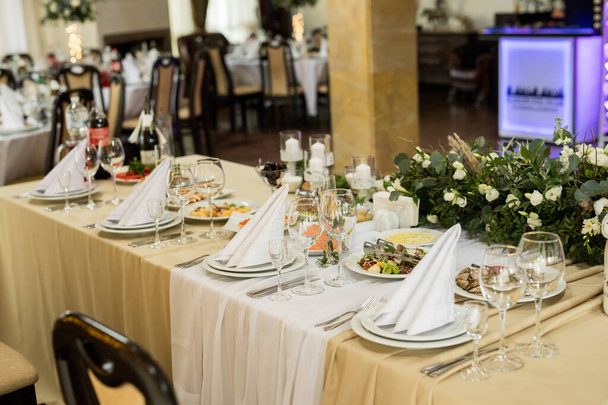 Primer plano de la mesa festiva con copas de vino, flores frescas en mantel beige - Foto, imagen