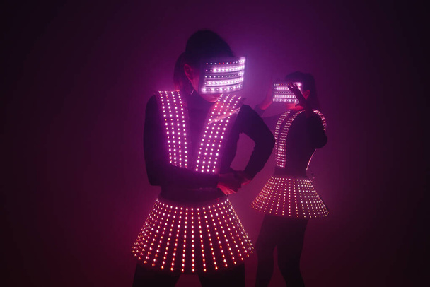 Две сексуальные танцовщицы танцуют в ультрафиолетовых костюмах. Вечеринки и танцы. - Фото, изображение