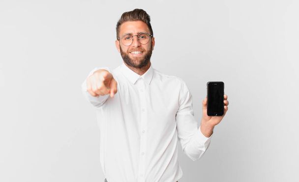 young handsome man pointing at camera choosing you and holding a cell - 写真・画像