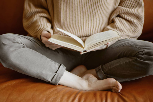 Cropped image of woman sitting on the couch and reading a book. - Valokuva, kuva