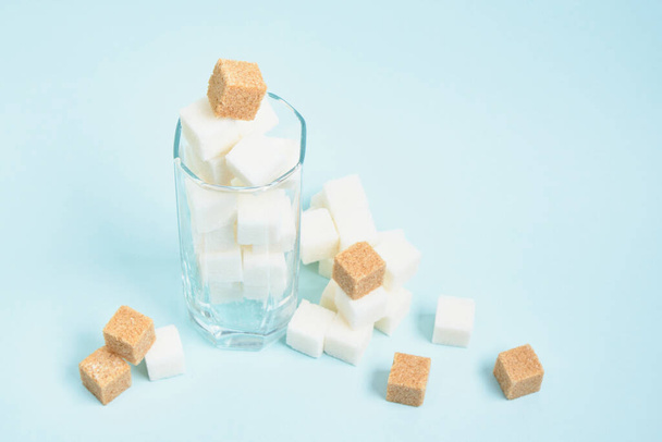 cubes of white and brown sugar in a glass and on a light blue and beige background copy space - Fotoğraf, Görsel