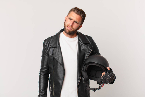 young handsome man feeling puzzled and confused. motorbike helmet concept - Φωτογραφία, εικόνα