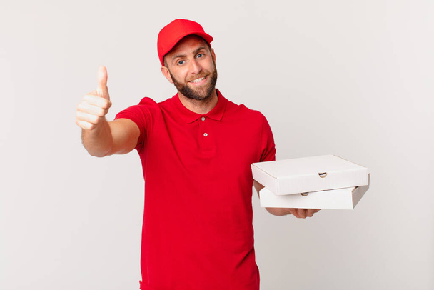 young handsome man feeling proud,smiling positively with thumbs up. pizza delivering concept - Zdjęcie, obraz