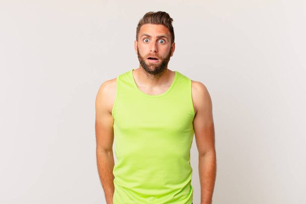 young handsome man looking very shocked or surprised. fitness concept - Foto, Imagen
