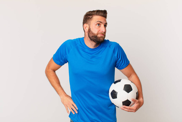 young handsome man shrugging, feeling confused and uncertain. soccer concept - Фото, зображення