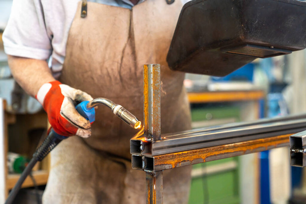 A metal worker welding and fabricating a metal frame for a garden patio - Photo, Image