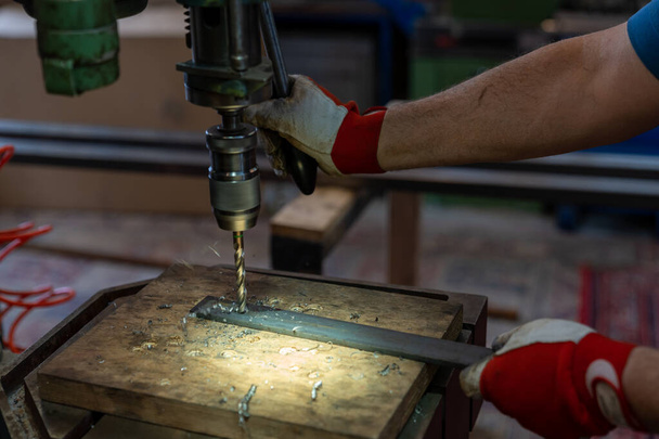 Robotnik metalowy wiercący dziury w metalu z wiertłem na ławce - Zdjęcie, obraz