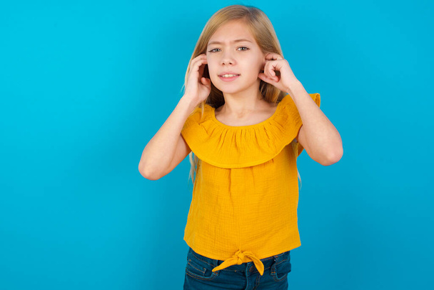 bambina che copre le orecchie con le dita con espressione infastidita per il rumore della musica ad alto volume. Concetto di sordo. - Foto, immagini