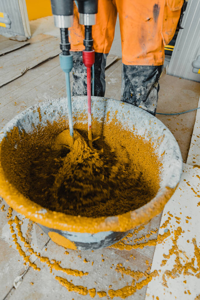 Photo en mouvement avec un travailleur mélangeant du mortier de polyuréthane coloré avec de la résine époxy - Photo, image