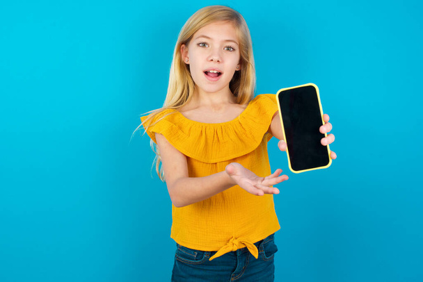 Dziewczynka prezentująca smartfona. Koncepcja reklamy. - Zdjęcie, obraz