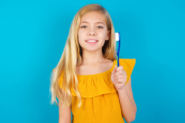 маленька дівчинка тримає зубну щітку і посміхається. Концепція стоматологічної медицини
. - Фото, зображення