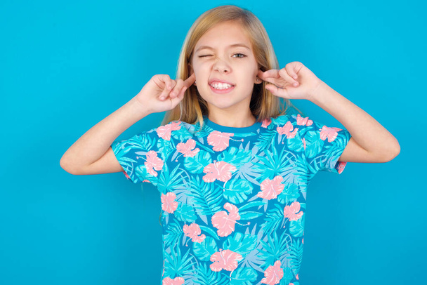 Happy little girl ignores loud music and plugs ears with fingers asks to turn off sound - Photo, Image