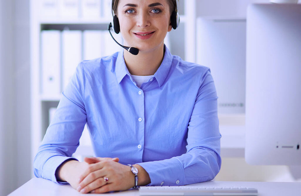 Serious pretty young woman working as support phone operator with headset in office - Fotó, kép
