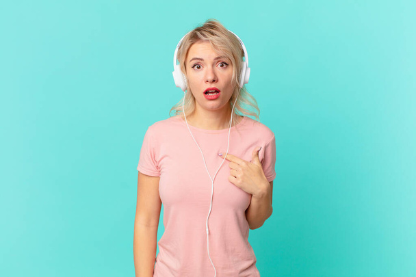 young pretty woman looking shocked and surprised with mouth wide open, pointing to self. listening music concept - Photo, Image