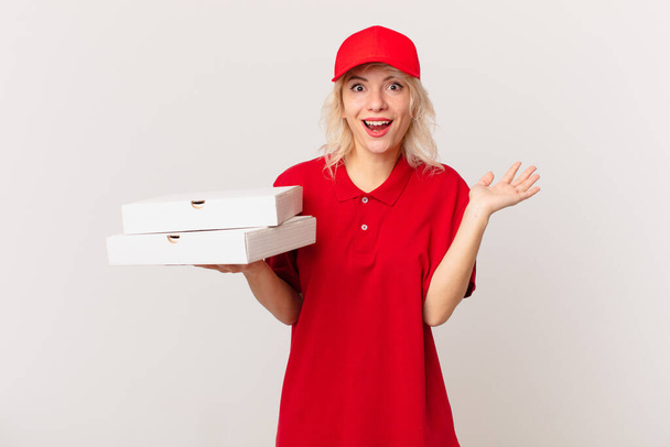 young pretty woman feeling happy and astonished at something unbelievable. pizza delivering concept - Foto, afbeelding