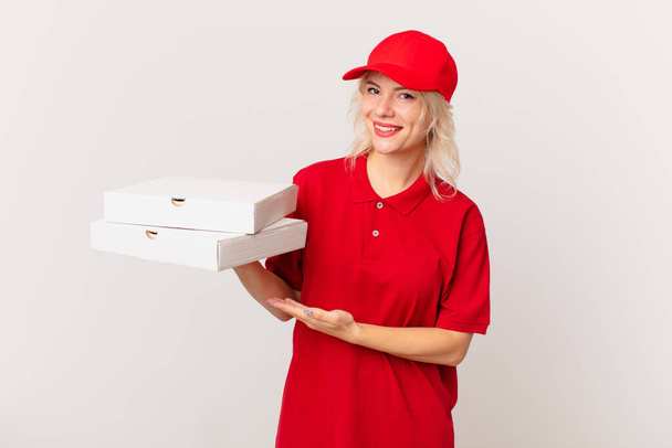 young pretty woman smiling cheerfully, feeling happy and showing a concept. pizza delivering concept - Фото, зображення