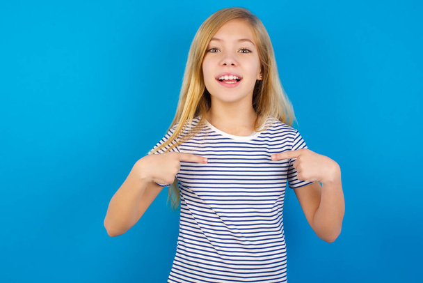 Kaukázusi lány csíkos inget visel a kék fal pont a testén, hogy jó hangulatban, miután vásárolni ment, és hogy sikeres vásárlások - Fotó, kép