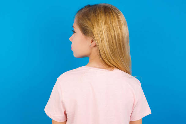 Pohled zezadu na bělošku v růžové košili u modré zdi. Studio Shoot. - Fotografie, Obrázek