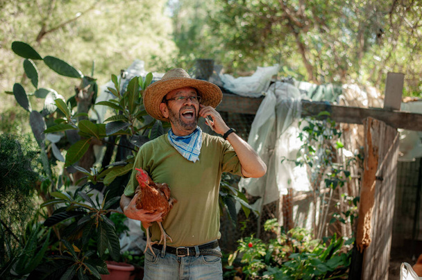Старик разговаривает по телефону в саду - Фото, изображение