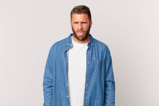 young handsome man feeling disgusted and irritated and tongue out - Photo, Image