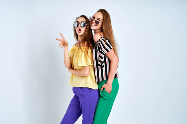 Zwei junge Frauen in stilvoller Kleidung Mode Schönheitsstudio auf weißem Hintergrund erschossen - Foto, Bild