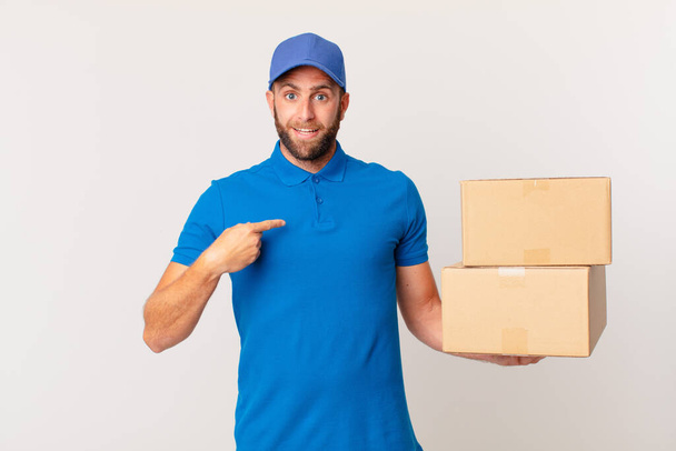 young handsome man feeling happy and pointing to self with an excited. package delivering concept - Valokuva, kuva