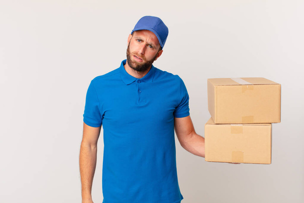 young handsome man feeling puzzled and confused. package delivering concept - Zdjęcie, obraz