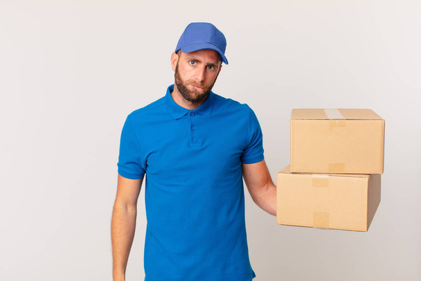 young handsome man looking puzzled and confused. package delivering concept - Valokuva, kuva