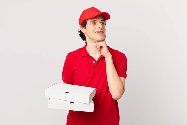 pizza deliver man smiling happily and daydreaming or doubting - Valokuva, kuva