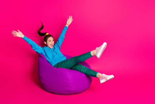 Full length photo of sweet cute woman dressed hoodie rest purple bean bag looking empty space isolated pink color background - Photo, image