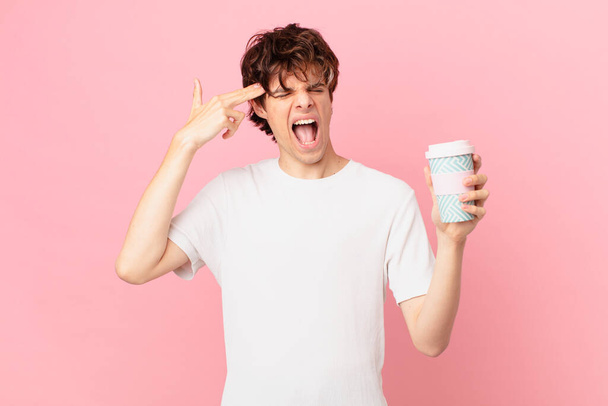 young man with a coffee looking unhappy and stressed, suicide gesture making gun sign - Foto, Bild