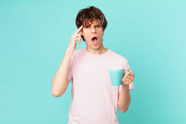 young man with a coffee mug looking surprised, realizing a new thought, idea or concept - Foto, Bild