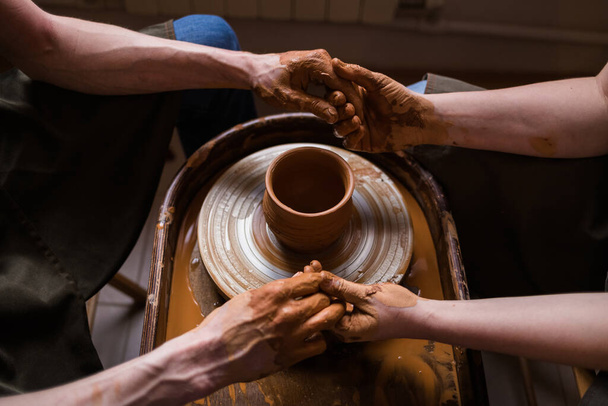 mains jointes d'un homme et d'une femme près d'un métier à tisser avec un pot d'argile - Photo, image