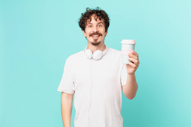 young man with a coffee looking happy and pleasantly surprised - Фото, зображення