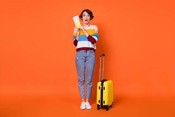 Photo of excited charming young lady dressed striped pullover luggage holding tickets isolated orange color background - Fotoğraf, Görsel