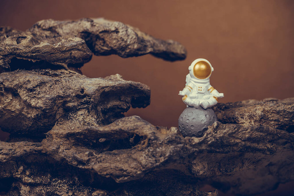 Astronaut wearing white space suit and helmet and meditating while sitting on the moon. Concept of cosmonautics, space travel, freedom, relaxing and peace of mind. - Foto, Imagem