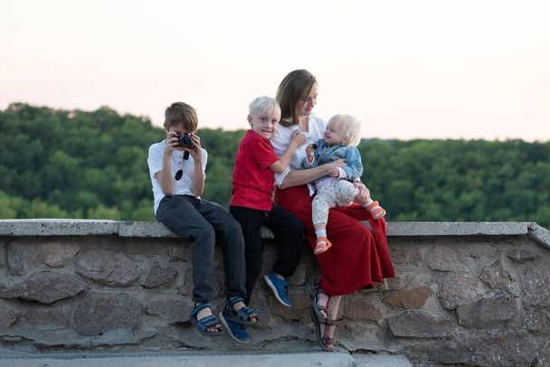 3人の子供を持つ若い母親は屋外で休んでいます。子供と旅行する - 写真・画像