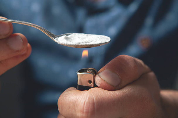 наркоман согревает ложку порошком - Фото, изображение