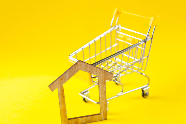 cesta y casa. concepto de compra de vivienda. sobre un fondo amarillo - Foto, imagen