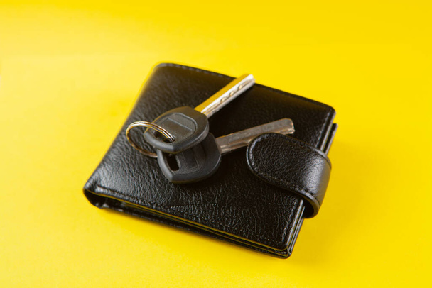 keys and black wallet on a yellow background - Zdjęcie, obraz