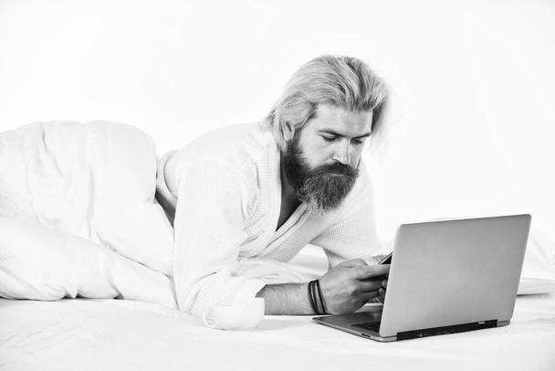 Social networks dependence. Screen Time and Insomnia. Happy hipster drink coffee in bed. Bearded man enjoy coffee and surfing internet laptop. Morning coffee routine. Social media. Modern life - 写真・画像