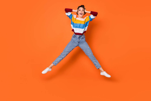 Full body portrait of cheerful person hands on head open mouth jump isolate don orange color background - Фото, изображение